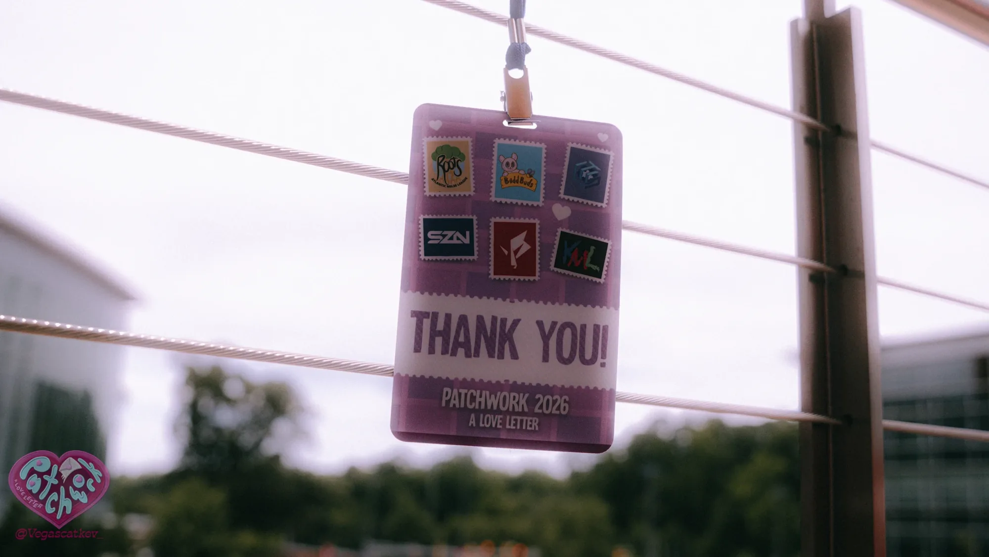Patchwork thank-you badge with sponsor stamps hanging on a railing outdoors